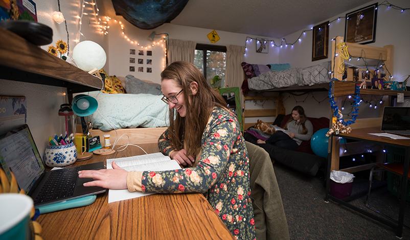 A student in her dorms, sitting at a desk